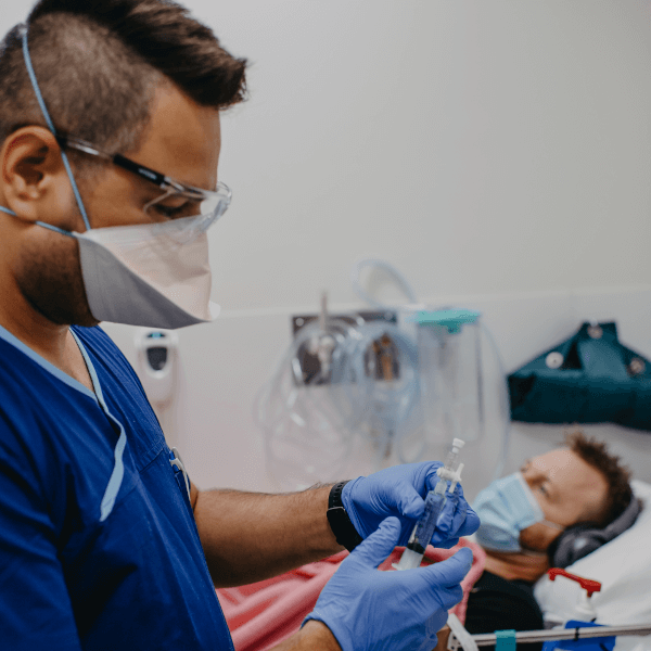 male clinical trials patient in bed with a male nurse standing nearby with a syringe  