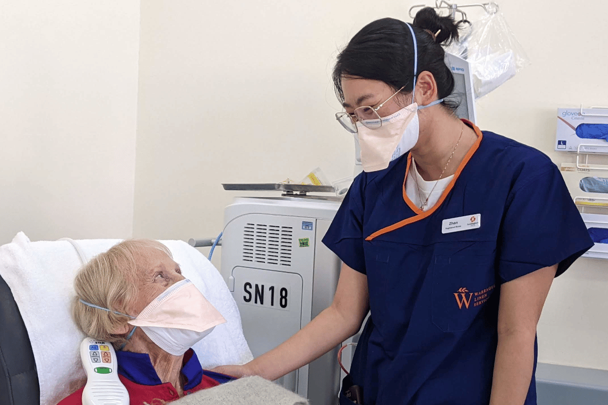 Dialysis nurse with older female patient in bed with mark