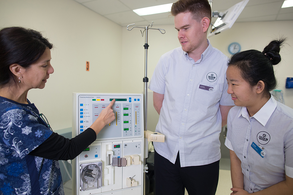 Deakin Uni trainer demostrating a piece of medical equipment to a male and female student nurse