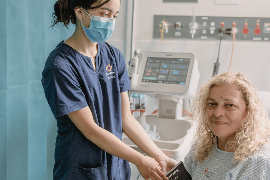 Female patient smiling to camera with nurse taking blood pressure