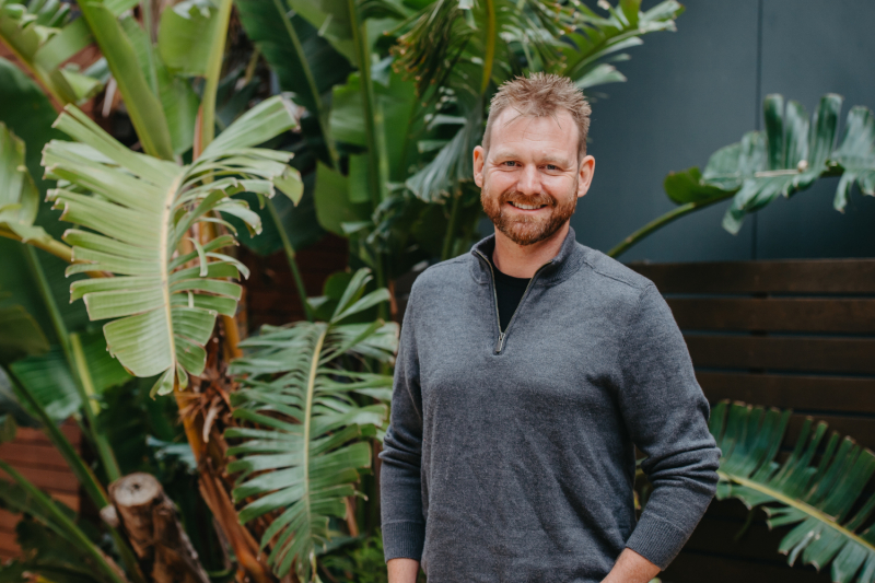 Trial Hub patient Steve standing in front of large green plant