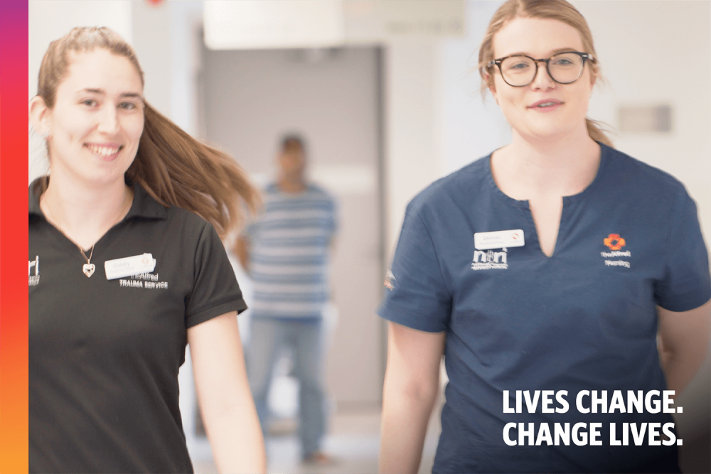 Two female nurses walking side by side down a corridor